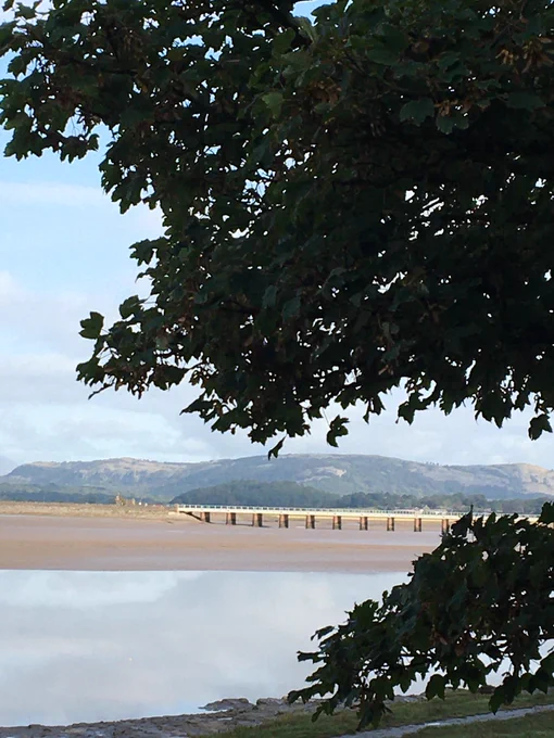 View across the Bay from Arnside. Low tide, hills in the distance and railway bridge.