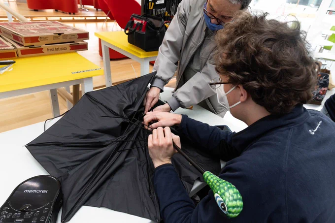 Two people work on a broken umbrella