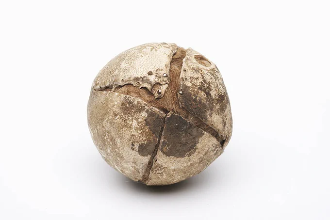 Very old-looking round brown and cream object with a cross-shaped split