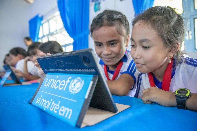 Two school girls look at a learning tablet. 