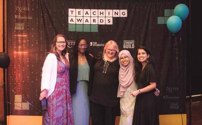 5 people posing for the camera after just winning an award.