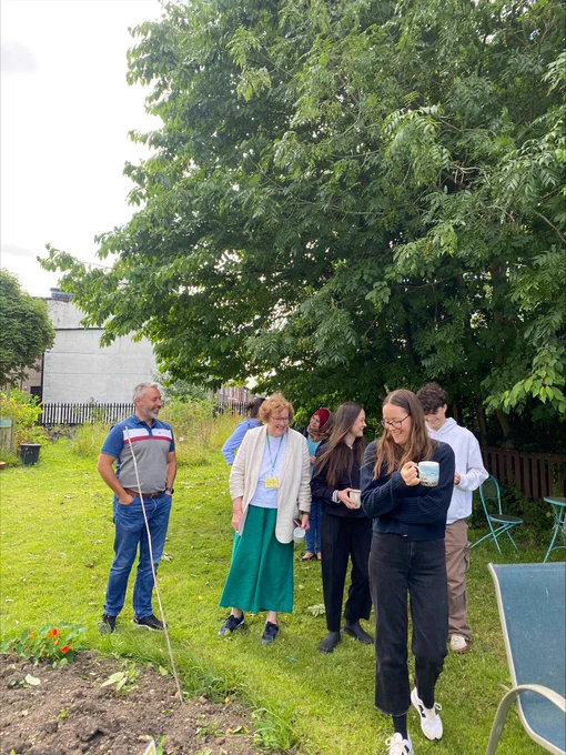 Group of smiling people walk around gardens 