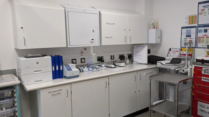 Empty clinic room with cupboards and a trolley 