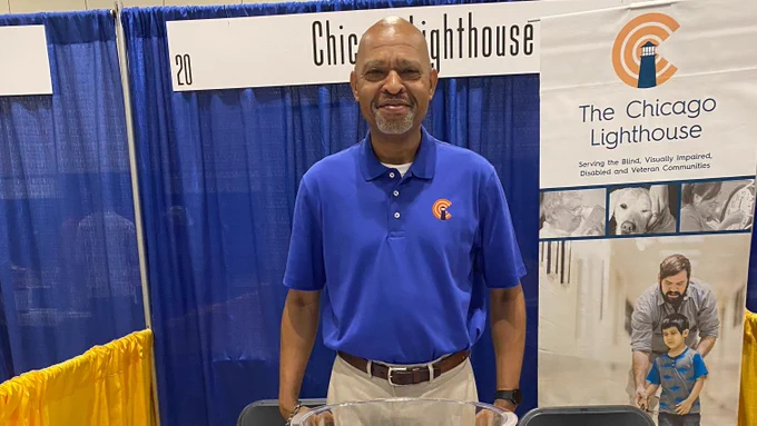 A friendly smiling man stands at the Chicago Lighthouse exhibit booth.