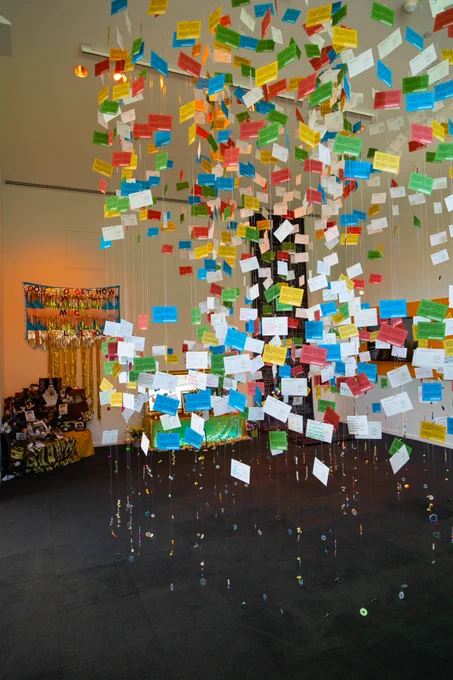 The I Choose to Remember Us Whole installation. Colored postcards hang from the ceiling in a circular form. 