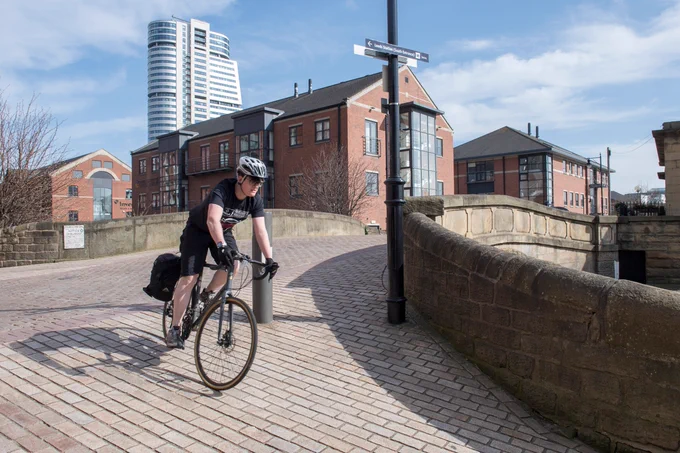 Person cycling to work on a multi-use path in an urban area