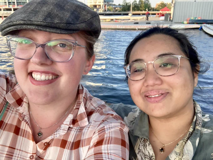 Alexei and Kawa, smiling at the camera with the waterfront behind them.