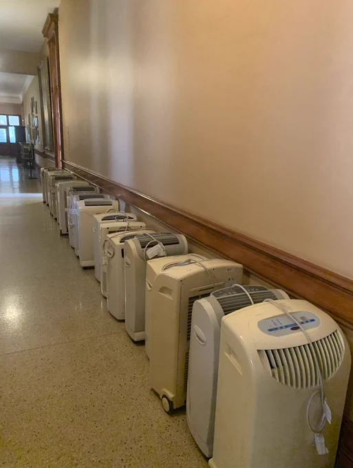 a line up of 10  air conditioning units lining the halls of Queen’s Park