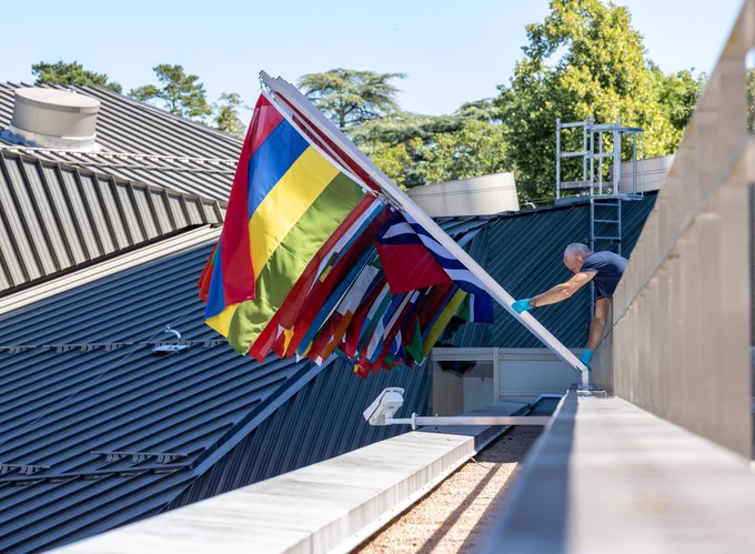 A WIPO staff places the flags of the Member States along the roof of WIPO Headquarters.