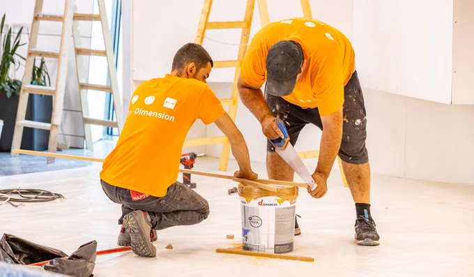 Support workers use a saw as they put together an exhibition panel for the Assemblies.