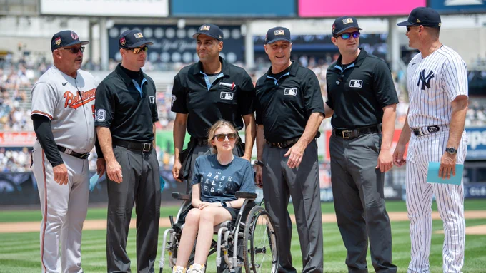 Sarah Langs poses for a photo with the umpiring crew and Yankees and Orioles personnel before Tuesday's game at Yankee Stadium.