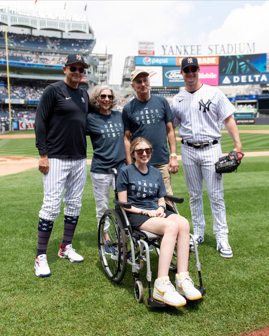 Sarah Langs poses for a photo on the field at Yankee Stadium with her parents, as well as Gerrit Cole and Aaron Boone.