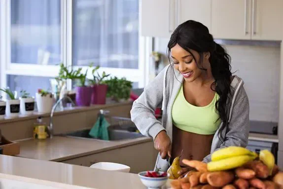 A woman chopping up fruit and vegetables in a kitchen