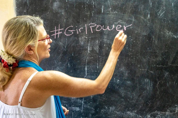UNICEF India Representative writing #GirlPower on a chalk board.