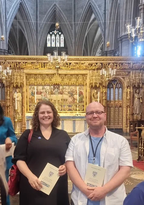 Eloise, in a black dress, next to me in a white shirt over a blue T-shirt. We are standing in front of the high altar at Westminster Abbey.