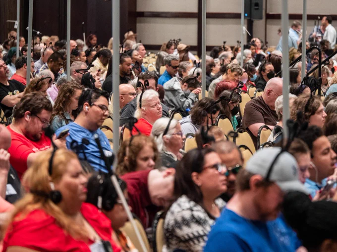 A large group of people sitting in a conference hall wearing butterfly antennae.