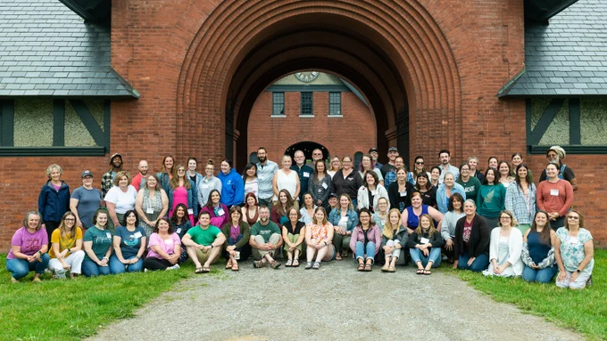 A group of program participants gather together in front of the Coach Barn for an all-cohort photo.