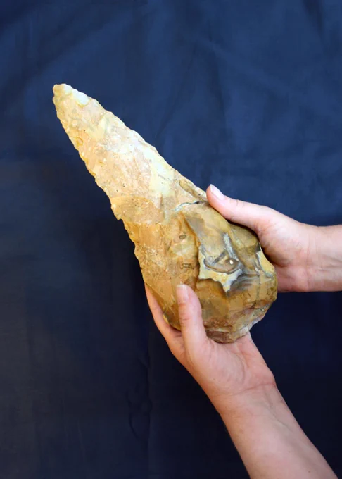 The Maritime Academy hand axe held in someone's hands for scale against a dark blue cloth 