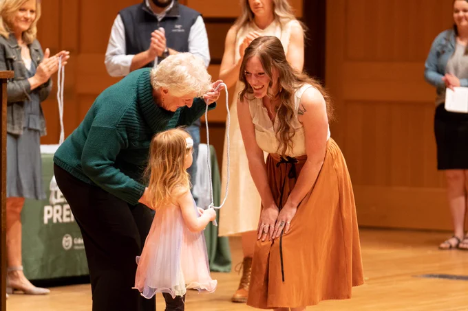 a graduate smiles at her daughter before she receives her cords