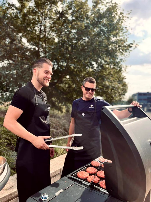 Arnold and myself standing in the sun smiling behind the barbecue