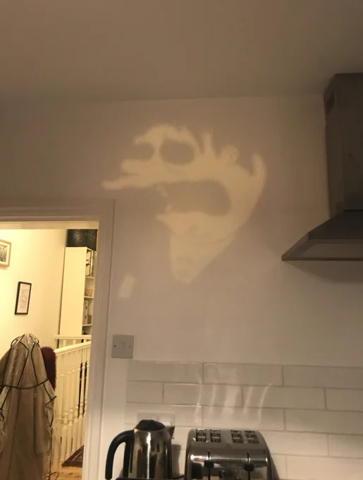 Reflection of Barney Gumble with no pupils on a white kitchen wall
