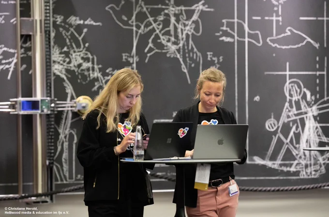 Zwei Frauen, die während der Veranstaltung vor ihrem Laptop stehen.