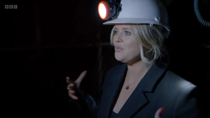 Emily talking underground, wearing a white hard hat with attached lamp