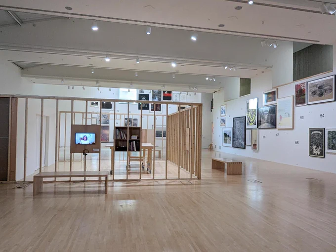 an empty room with wooden partitions and pictures on the wall, part of an exhibition at the Henry Art Gallery called Taking Care