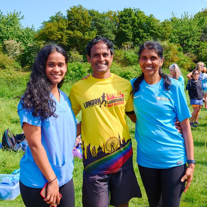 Image of three parkrunners standing together one is wearing blue scrubs, another a blue top and the other a race top.