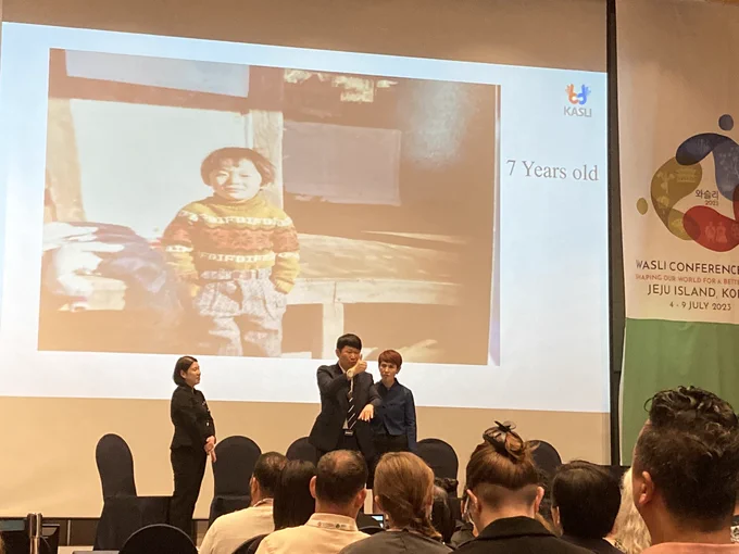 Se-woong Yoon and interpreters, powerpoint of him as a 7-year old in the background