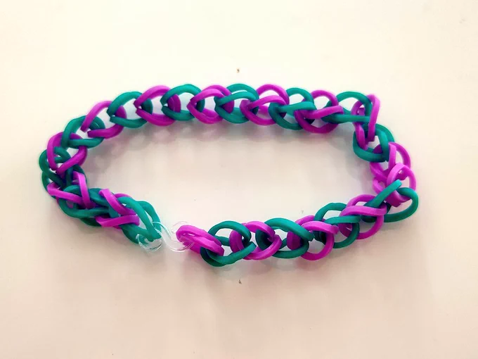 Foto de una pulsera infantil de gomas entrelazadas, turquesa y morada.
