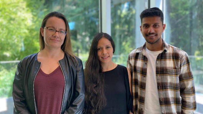 Alejandra Chacon Gallardo, Katherine Matos and Jofri Issac stand in the RRU library. 