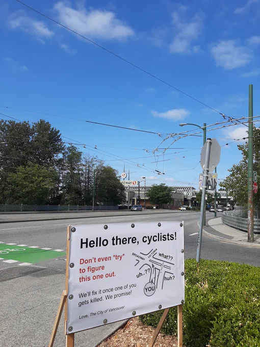 Sign near otherwise unprotected green paint bike crossing crossing 6 lane stroad: Hello there, cyclists! Don't even try to figure this one out. We'll fix it once one of you gets killed. We promise! Love, The City of Vancouver. Illustration on sign depicts complex intersection with labeled with "what?" comments and question marks. 