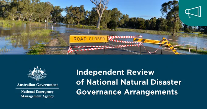 Yellow "Road Closed" sign and red and white tape over a flooded road. More flooding on the left next to the road, with trees at the back and blue sky: "Independent Review of National Natural Disaster Governance Arrangements"