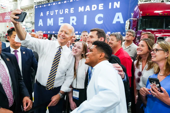 President Joe Biden takes a selfie with guests following his remarks.
