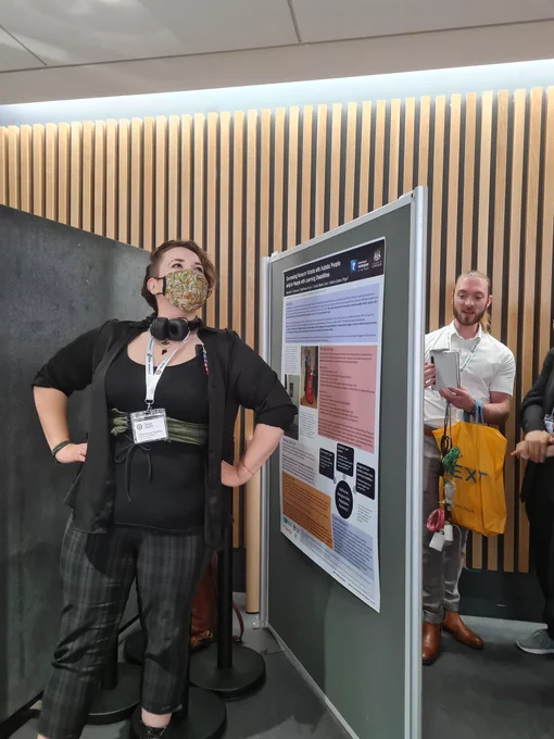 Harriet posing next to their poster