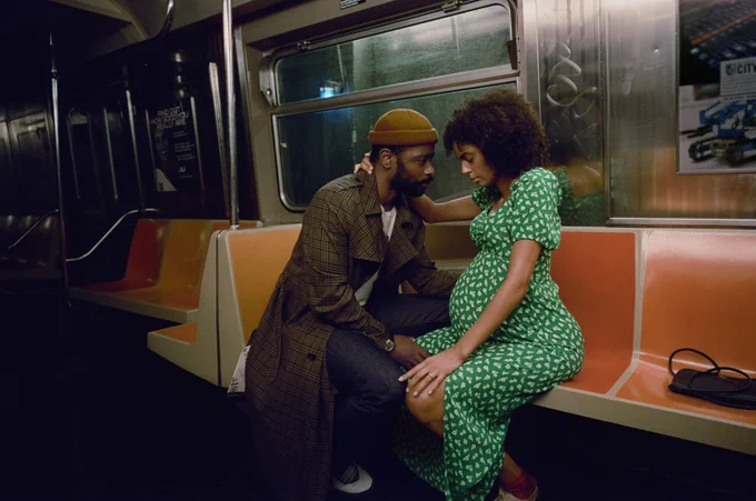A couple sits aboard a New York City subway. The character of Apollo (played by LaKeith Stanfield in The Changeling) stares lovingly at his pregnant wife Emma (played Clark Backo) who gazes down at her baby bump.
