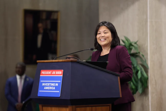 Acting Secretary of Labor Julie Su speaks at the Good Jobs, Great Cities Academy launch event. She is speaking from a podium with a sign on front that states "President Joe Biden, Investing in America."