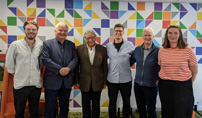 6 people standing in front of a geometric wall design.