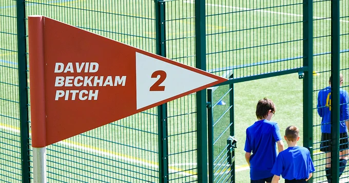 Boys football team talk on to a pitch at St George's Park under the 'David Beckham Pitch' sign