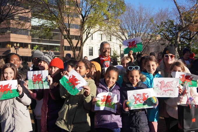 Welsh Minister for Economy Vaughan Gething poses with primary school students from John Ross Elementary school who drew their own Welsh flags in advance of Soccer in the Circle.