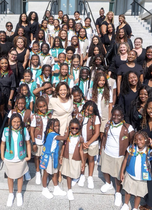 Vice President Harris poses for a photo on the Navy Steps with the Zawadi Girl Scout Troop 3246.