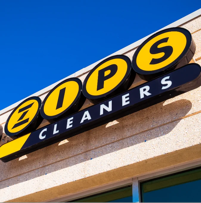 ZIPS Cleaners famous black and gold logo proudly shining on a storefront. 