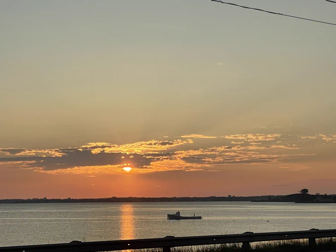 Cloudy sunrise with fishing boat on the water.