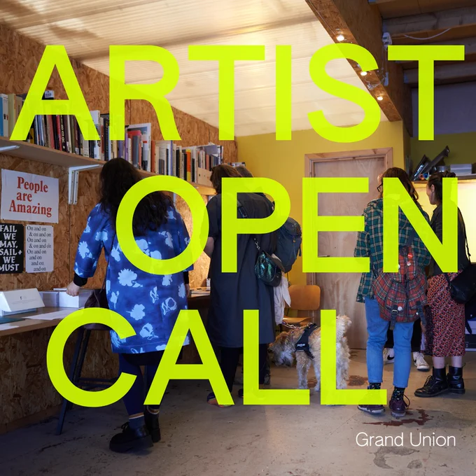 An image of a group of people looking around a warmly lit artist studio with a variety of posters containing text on the wall. At the top of the wall there is a large shelf of books. Over the image there is large text in bright green which reads “ARTIST OPEN CALL”