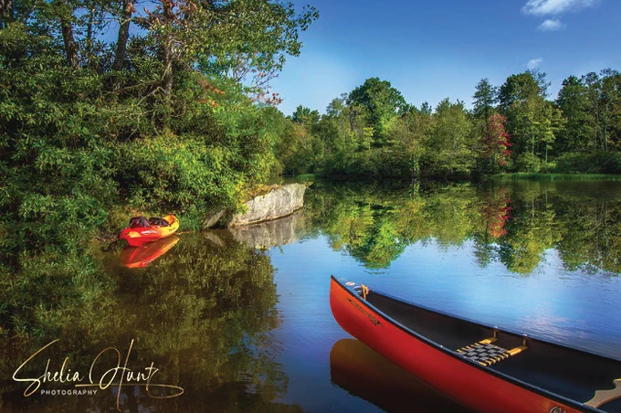 The beautiful Price Lake on a perfect summer day, with red canoe and kayak floating in the water, which has stunning reflections from the surrounding nature. Artwork is from th Fine Art Gallery of Shelia Hunt.