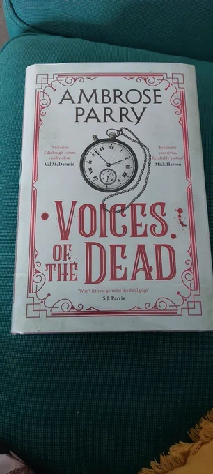 Cover of a hardback book with an old fashioned pocket watch and the words Ambrose Parry: Voices of the Dead 