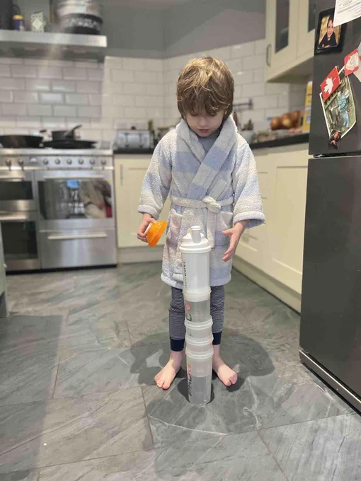 Child in a kitchen stacks cups high 