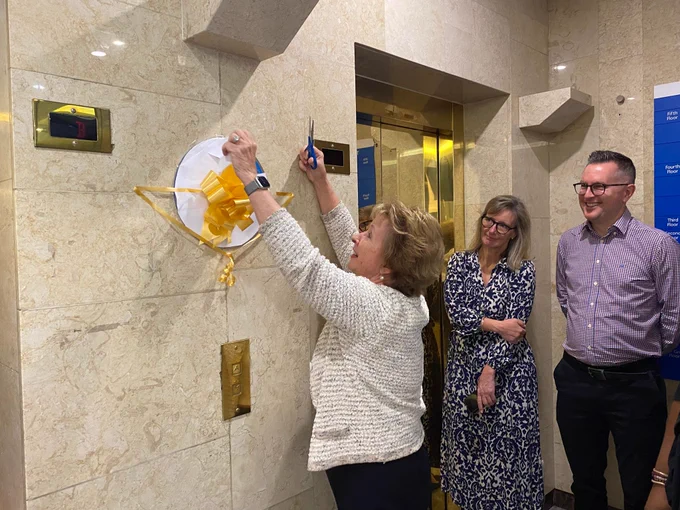 Chair Eileen Taylor cutting the ribbon of the plaque.