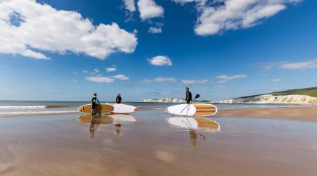 Paddle boarders on a beach in Compton Bay, Isle of Wight. Getty Images.